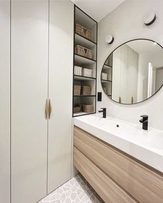 a bathroom with a large mirror above the sink and shelves on the wall next to it