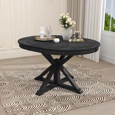 a black table sitting on top of a wooden floor next to a vase filled with flowers