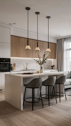 a kitchen island with stools next to it and lights hanging from the ceiling above