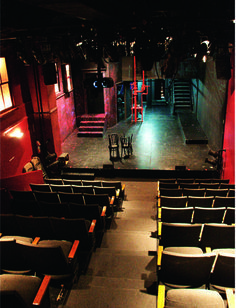 an empty stage with chairs and steps leading up to the second floor, at night