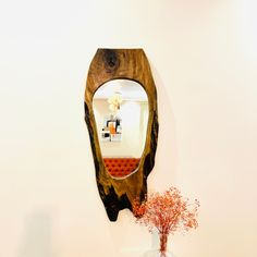 a wooden mirror sitting on top of a wall next to a vase filled with flowers