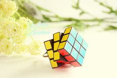 a rubik cube ring sitting on top of a white table next to some flowers