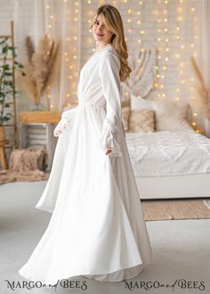 a woman standing in front of a bed wearing a white dress