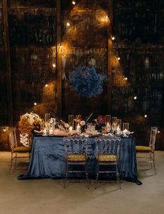 the table is set up with blue linens and candles for an elegant dinner party