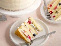 three slices of cake on white plates with silverware next to one slice and berries