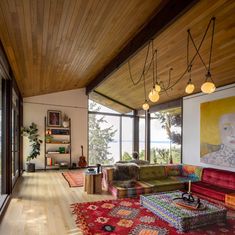 a living room with large windows and lots of furniture on the wooden floored area