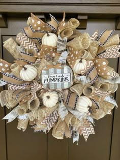 a burlap and ribbon wreath with pumpkins on the front door for fall