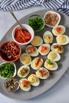 an assortment of deviled eggs on a platter with condiments and seasoning