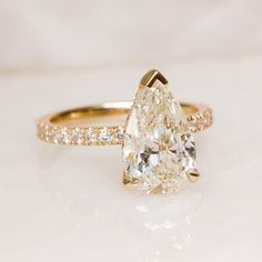 a pear shaped diamond ring with pave diamonds on the band