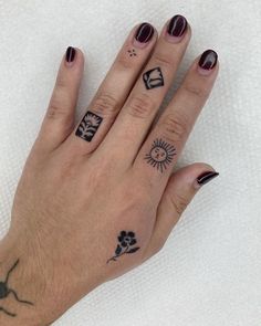 a woman's hand with tattoos on it and two fingers that have small symbols on them