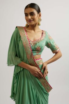 Channel your feminine energy with this elegant sari set. The breezy sleeve blouse in soft viscose pairs beautifully with a georgette sari featuring playful frills and frowns. Perfect for adding a touch of grace and style to any special occasion. Green Sharara With Ruffles And Traditional Drape, Green Ruffled Sharara With Traditional Drape, Elegant Green Sharara With Ruffles, Elegant Green Ruffled Sharara, Designer Georgette Blouse With Ruffles, Pista Green Georgette Blouse For Wedding, Elegant Green Pre-draped Saree For Transitional Season, Traditional Designer Blouse Piece With Ruffles, Green Bollywood Sharara With Ruffles