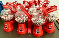 several red snow globes with bows and sprinkles in them on a table