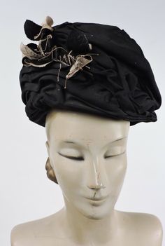 VICTORIAN 1890’S BLACK RUCHED SILK WIRED TORQUE HAT W LEAVE TRIMS DATING TO THE VICTORIAN 1890’S FASHIONED OF BLACK SILK FAILLE OVER A WIRED CAGE BASE WITH RUCHED GATHERS THROUGHOUT  THE FRONT RISES 5 1/2 INCHES IN HEIGHT WITH THE REAR TWO INCHES IN HEIGHT AND BLACK WIRED LEAVES TRIM THE FRONT, I SUSPECT THAT THEY WERE ONCE FLORALS THAT ARE NOW MISSING, ONES COULD EASILY BE RE-ADDED.    THE INTERIOR IS LINED IN BLACK POLISHED COTTON. UNIVERSAL IN SIZE AS IT IS WORN ATOP THE HEAD WITH A HAT PIN Victorian Evening Hats For Kentucky Derby, Victorian Cloche Hat For Evening, Black Victorian Hat For Evening, Black Victorian Evening Hat, Vintage Black Fitted Headpieces, Black Fitted Vintage Headpiece, Vintage Black Headpiece For Kentucky Derby, Vintage Black Headpieces For Kentucky Derby, Vintage Fitted Bonnet For Costume