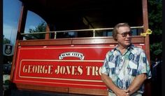 a man standing in front of a sign for george jones'train at an amusement park