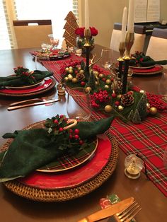 the table is set for christmas dinner with red and green plates, napkins, silverware