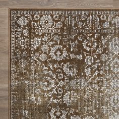 a brown and white area rug on top of a wooden floor with an ornate design