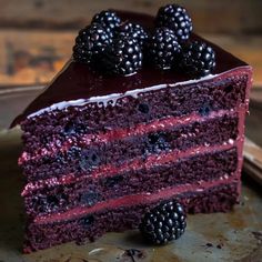 a slice of red velvet cake with blackberries on top and the rest of it