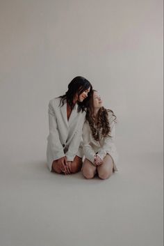 two women are sitting on the floor and one is holding her head