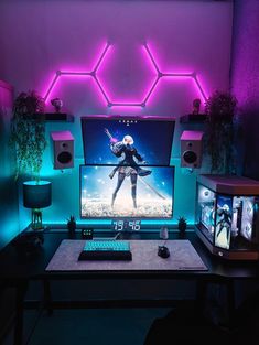 a desk with a computer and speakers on it in front of a purple wall that has neon lights