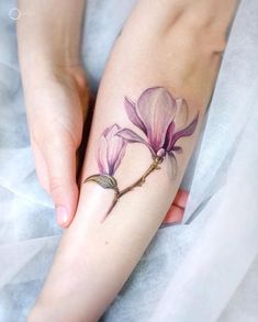 a woman's hand with a flower tattoo on her left wrist and the other arm