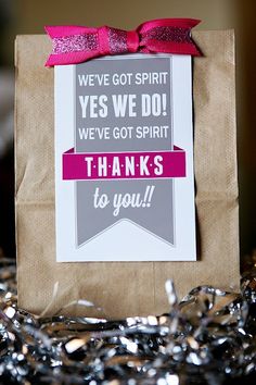 a brown paper bag with a pink ribbon on it and some silver tinsel around it