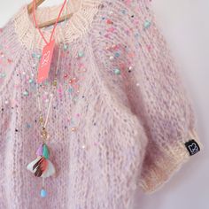 a pink sweater with colorful beads and a tassel hanging from it's back