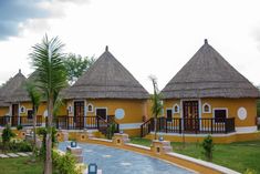 two yellow buildings with thatched roofs and balconies