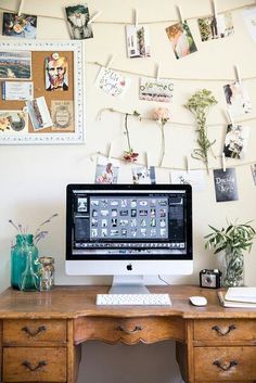 a desk with a computer and many pictures on the wall