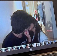 a man and woman are kissing on the screen of a laptop computer as they look into each other's eyes