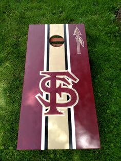 a close up of a cornhole board on the grass with st louis logo painted on it