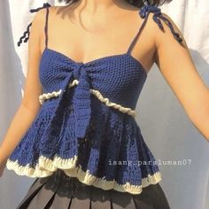 a woman wearing a blue crochet top and black skirt