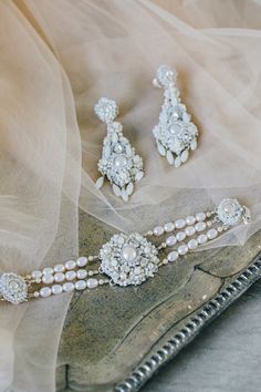 the bride's jewelry is displayed on top of her wedding dress and veils