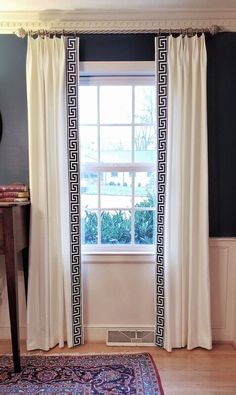 a living room with a rug, window and white curtains on the windows sill