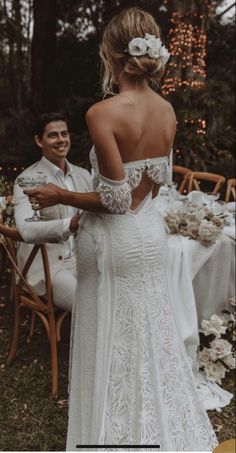 a man and woman standing next to each other in front of a table with flowers