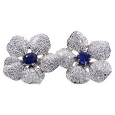 Beautifully designed and masterfully handcrafted in platinum, these 1950s ear clips make a statement on the ear. 5 realistically fashioned flower petals are set with 125 bright white and sparkly round brilliant cut diamonds on each earring, with an approximate total weight of 10 carats. The centers are 2 matched oval wonderfully saturated blue sapphires, weighing approximately 1.60 each. The earrings are secured by a post and a omega clip back Blue White Earrings, Sapphire Diamond Earrings, Saturated Blue, Sapphire And Diamond Earrings, Ear Clips, The Ear, South Sea Pearls, Sea Pearls, Emerald Jewelry