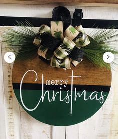 a merry christmas sign hanging on the side of a door with pine cones and evergreens