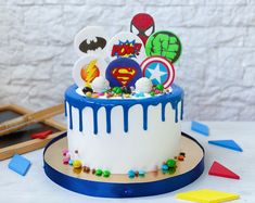 a birthday cake decorated with fondant and superheros on the top is ready to be eaten