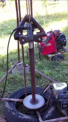 an old fashioned machine is sitting in the grass next to some tires and other tools