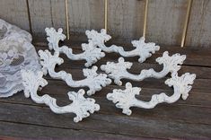 several white decorative objects sitting on top of a wooden table next to a lace curtain