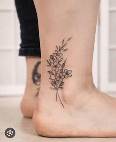 a woman's foot with a small flower tattoo on the side of her leg