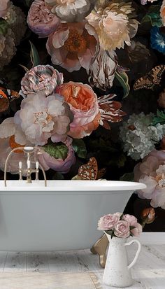 a bath tub sitting next to a wall covered in flowers