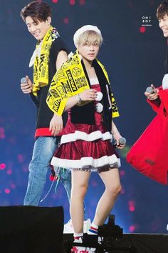 two young people on stage with one holding a microphone and the other wearing a santa hat