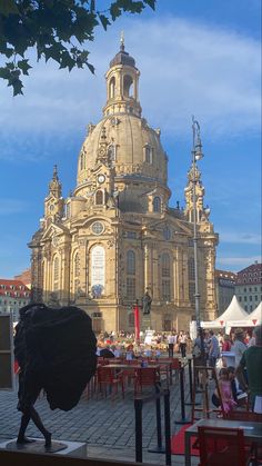 a large building with many people sitting at tables in front of it and one person walking by