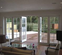 a living room filled with furniture and lots of glass doors leading to an outside patio