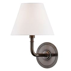 a wall light with a white shade on the side and a brown metal arm that is attached to it