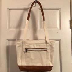 Beige Canvas Shoulder Mini-Tote Bag With Brown Leather Trim Bottom And Shoulder Straps. 2 Outside Pockets- 1 Zippered, 1 Inside Picket. Zippered Top Closure. Measurements: 12”W X 10”H X 3.5”D X 14” Drop. Brand New. Never Worn. No Tags. White Bucket Shoulder Bag With Canvas Lining, White Shoulder Bag With Canvas Lining For Shopping, Beige Tote Canvas Bag With Zipper Closure, Cream Canvas Bucket Shoulder Bag, White Bucket Bag With Canvas Lining, Cream Canvas Bucket Bag For Travel, White Leather Canvas Bag With Handles, Casual White Canvas Bag With Leather Handles, White Leather Canvas Bag