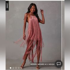 a model wears a pink dress with fringes on the bottom and sides, in front of a gray background