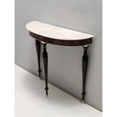 a white marble top console table with black legs and an intricately carved design on the edge