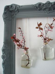 two vases with flowers in them hanging on a wall