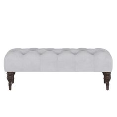 an upholstered bench with wooden legs and buttons on the back, in grey fabric